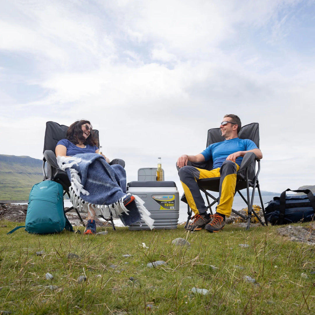 Two people sitting in Vango Atlas Chair outdoors with a scenic background