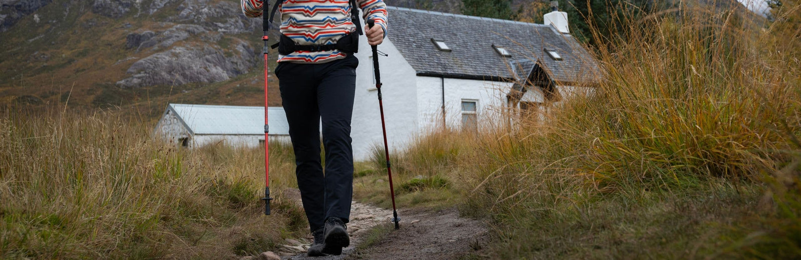 A hiker using the Vango Basho Walking Poles on a countryside path, highlighting their suitability for outdoor walking and trekking.