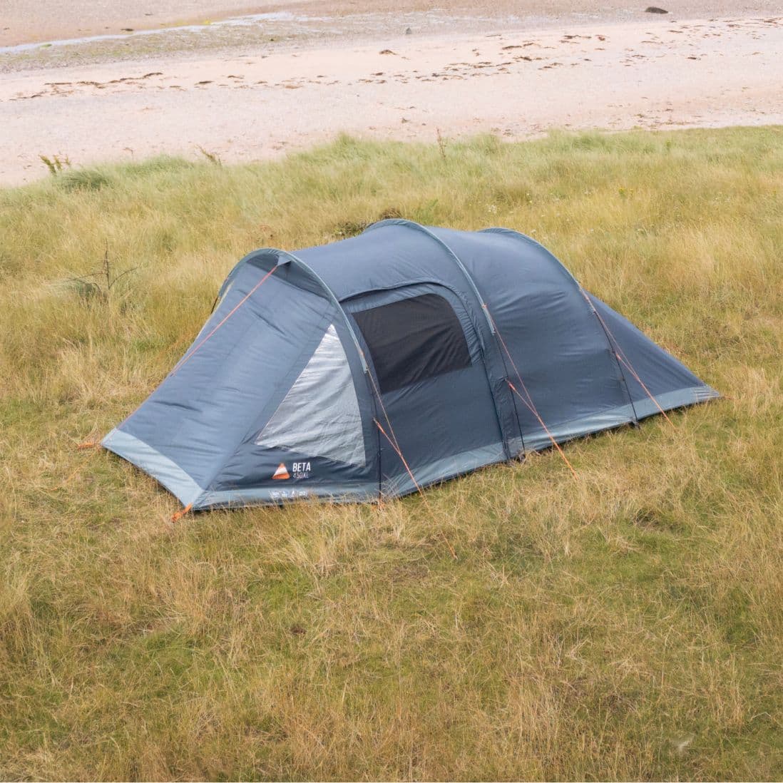 Aerial view of Vango Beta 450XL tent pitched in a grassy area near the beach, highlighting its compact yet spacious design.