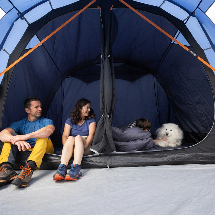 Two people and a dog inside a Vango Capri 400 Tent on a clear day.