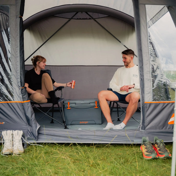 Couple sitting in the Vango Cove III Air Low Awning, illustrating its comfortable interior for relaxing on camping trips.