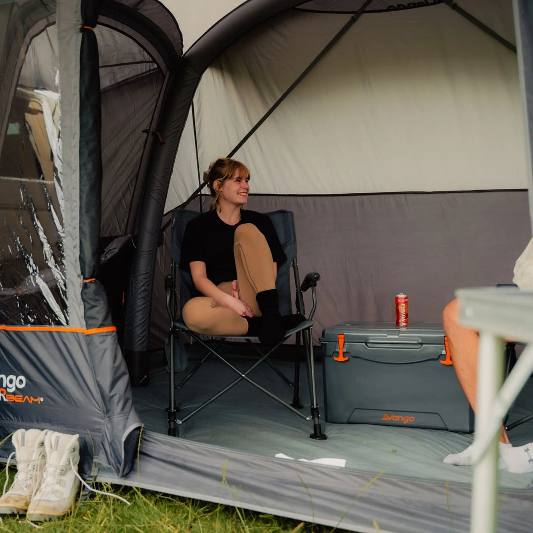 Woman sitting inside the Vango Cove III Air Low Awning, highlighting the comfort and space of the interior.