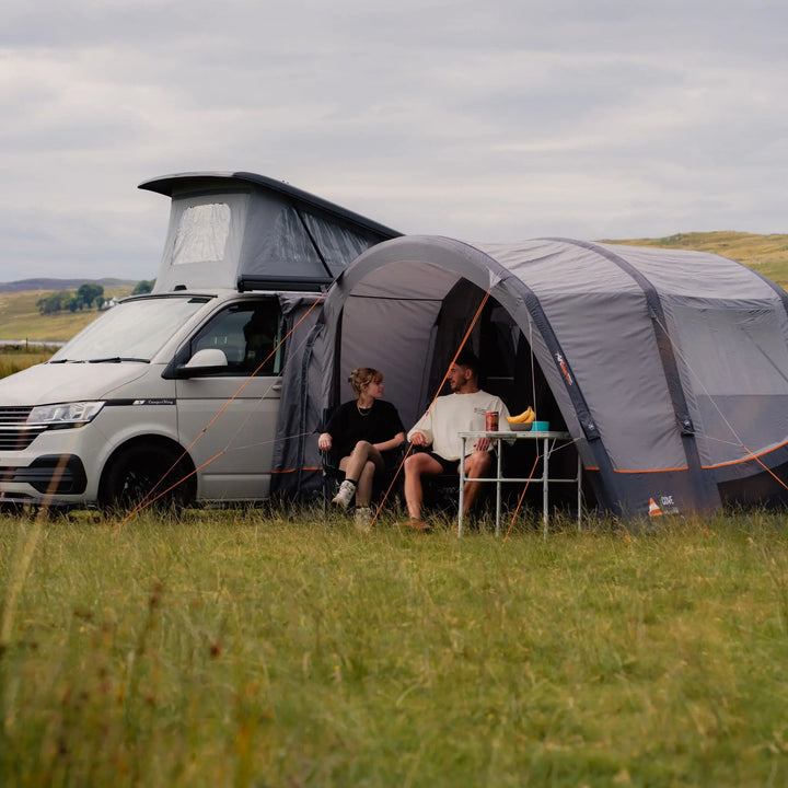 Side view of the Vango Cove III Air Low Awning connected to a VW campervan, showcasing its size and versatility in outdoor settings.