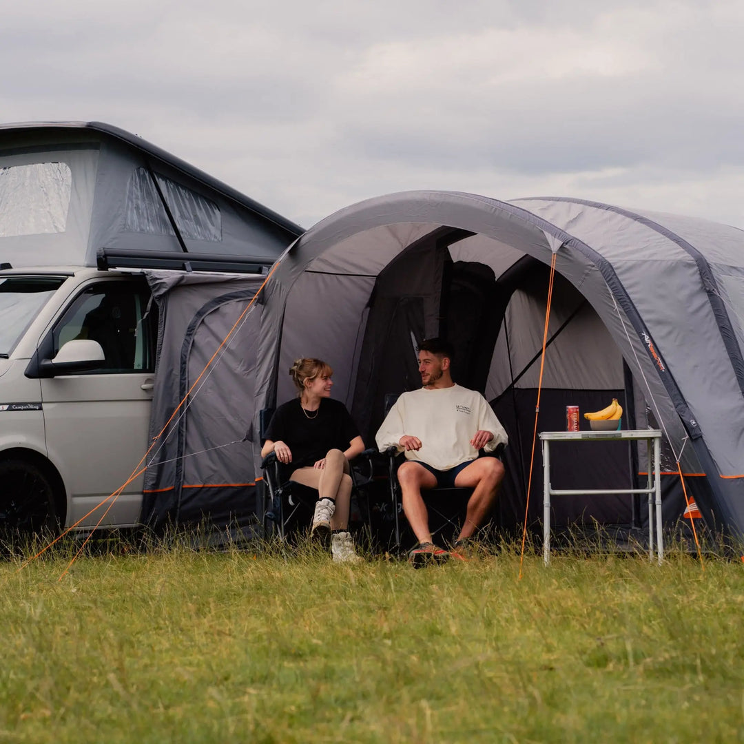 Couple enjoying the built in sun canopy on the Vango Cove III Air Low Awning, highlighting the shaded space.