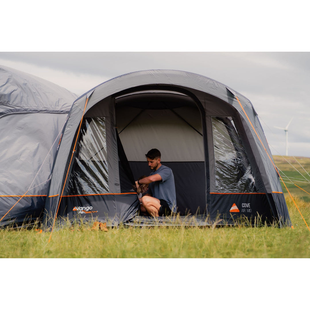 A person setting up the interior of the Vango Cove III Air Inflatable Awning, showcasing its roomy layout and durable construction.