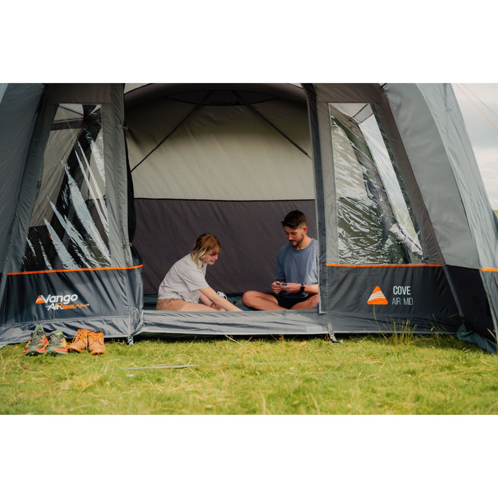 Two people sitting inside the Vango Cove III Air Mid Awning, enjoying the comfortable and functional extra living space.