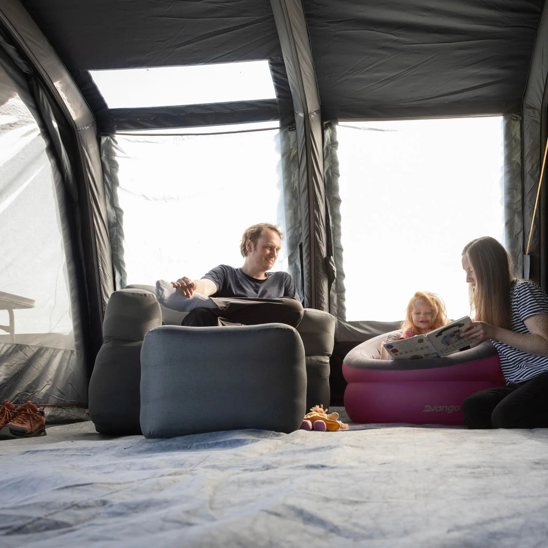 Family in the living area of the Vango Edition 60 Sherwood Air Tent reading a book to a child.