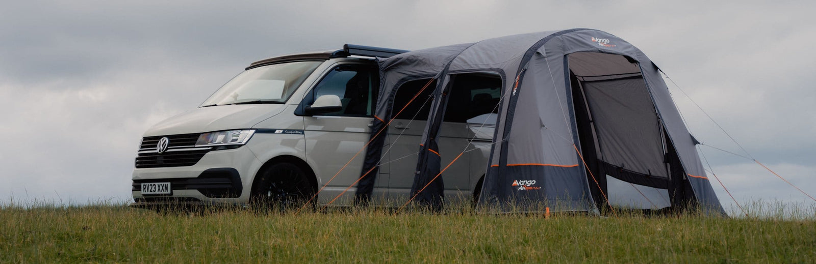 VW campervan with the Vango Faros III Air Low drive away awning attached, providing extra living space and a secure inflatable air awning setup in a scenic outdoor setting.