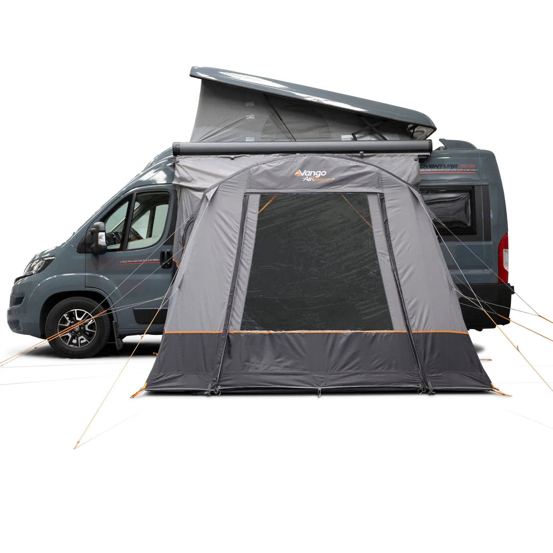 A Vango Faros III Air Mid Drive Away Awning with mesh windows and orange guy lines, shown attached to the side of a dark gray camper van on a white studio background.