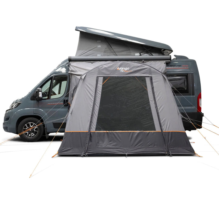 A Vango Faros III Air Mid Drive Away Awning with mesh windows and orange guy lines, shown attached to the side of a dark gray camper van on a white studio background.