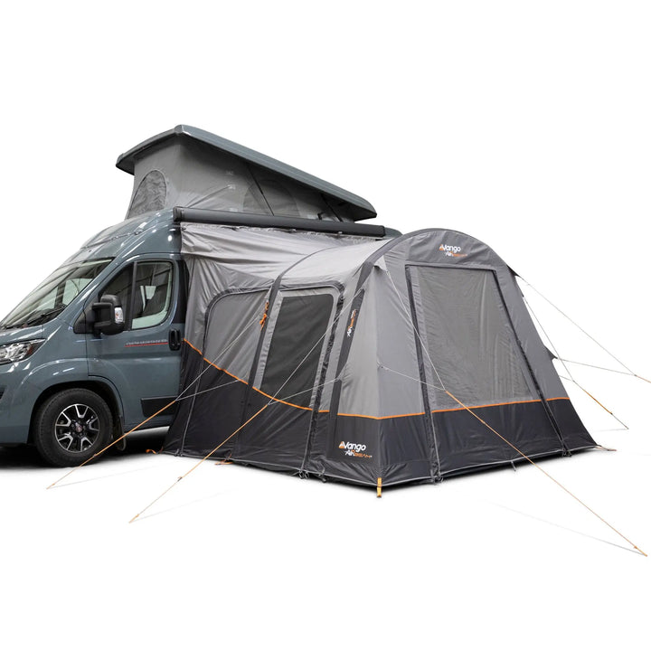 A Vango Faros III Air Mid Drive Away Awning with orange accents, shown attached to the side of a blue-gray van with its roof raised, on a plain white background.