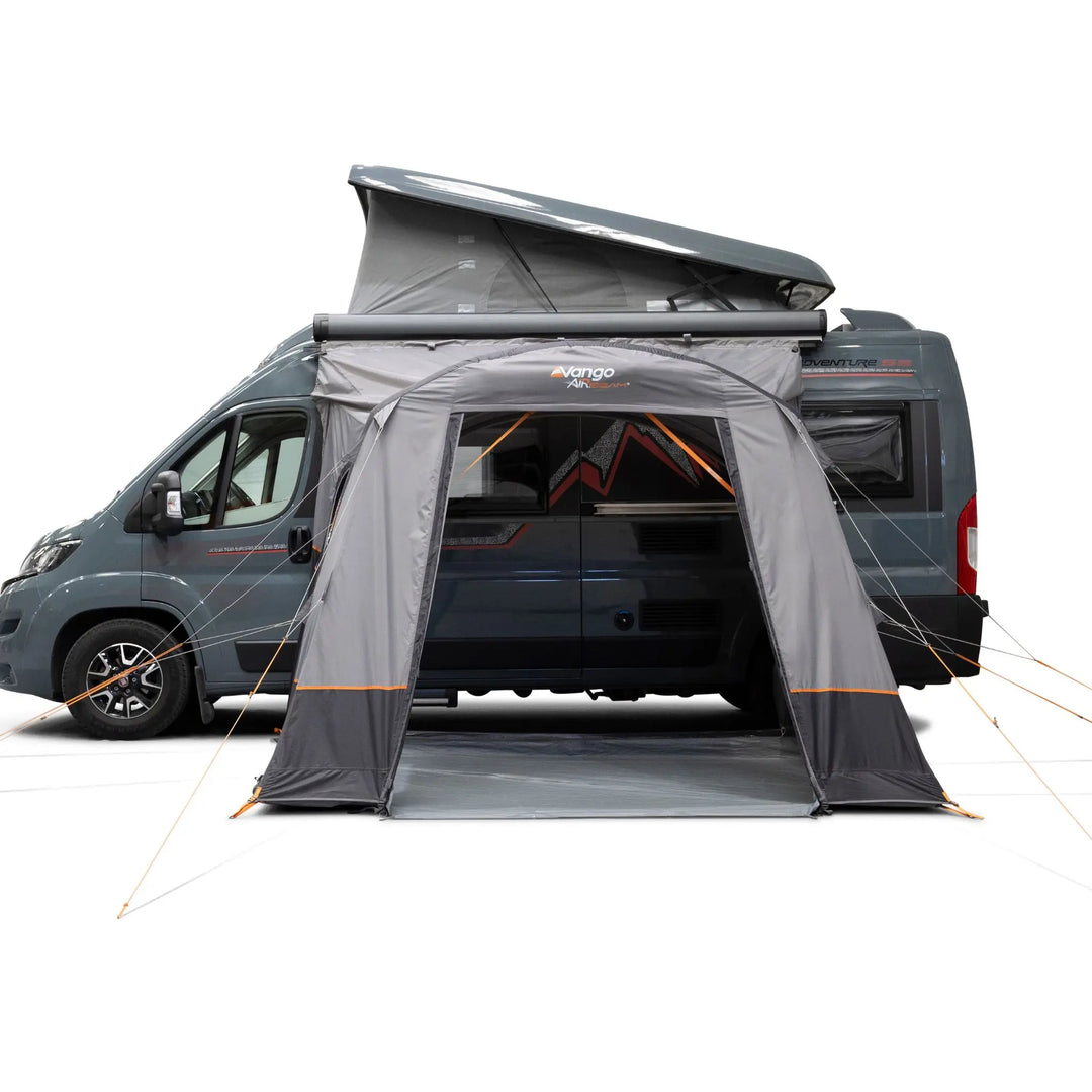 A Vango Faros III Air Mid Drive Away Awning with orange accents, shown attached to the side of a dark grey van on a clean white background.