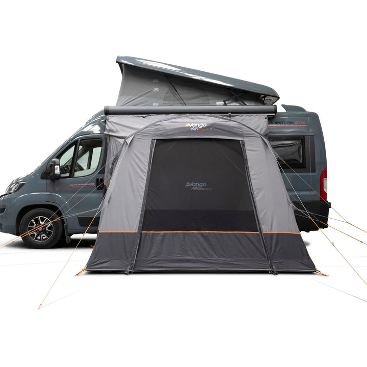 A Vango Faros III Air Mid Drive Away Awning attached to the side of a dark grey motorhome, shown on a clean white studio background. The awning has a mesh front door, orange guy lines, and visible Vango branding.
