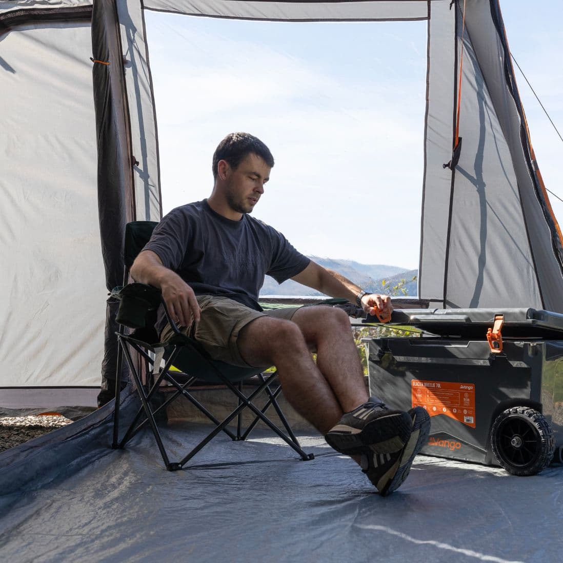 Interior view of the Vango Faros III Low Drive Away Awning, showing a camper seated in the living area with ample space for comfort and gear.