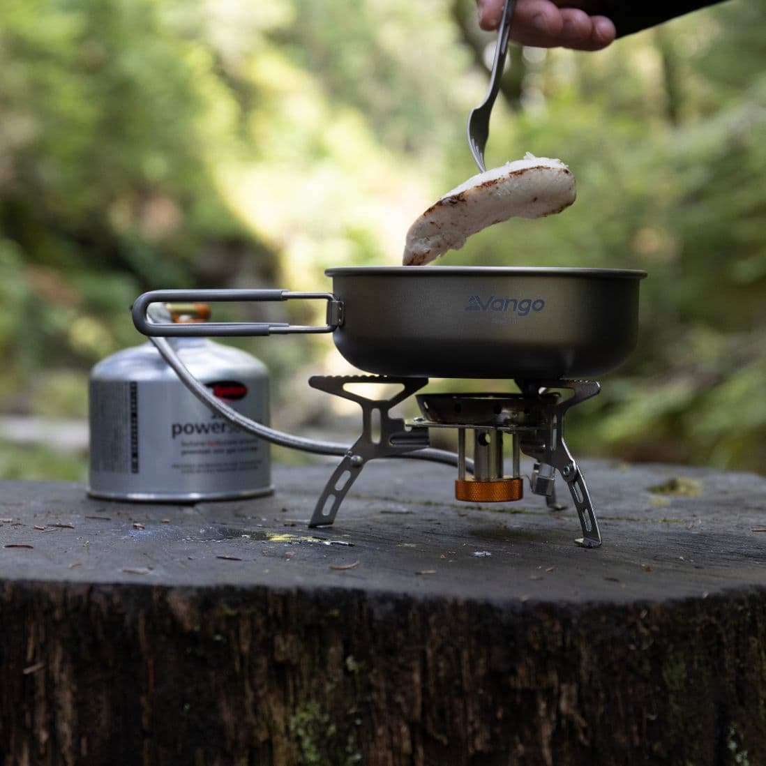 Close-up of Vango Folding Gas Stove with Windshield and Piezo while cooking food, showcasing its lightweight design for hiking and its stability for outdoor use.