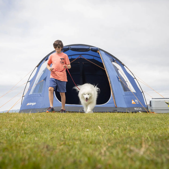 Person with a dog standing in front of a Vango Iris 500 Tent on grass