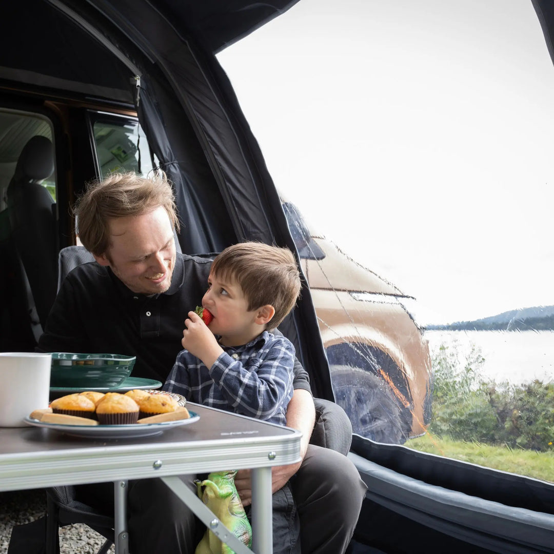 Man and child in a Vango Kela Edition 60 Drive Away Awning by a lake.