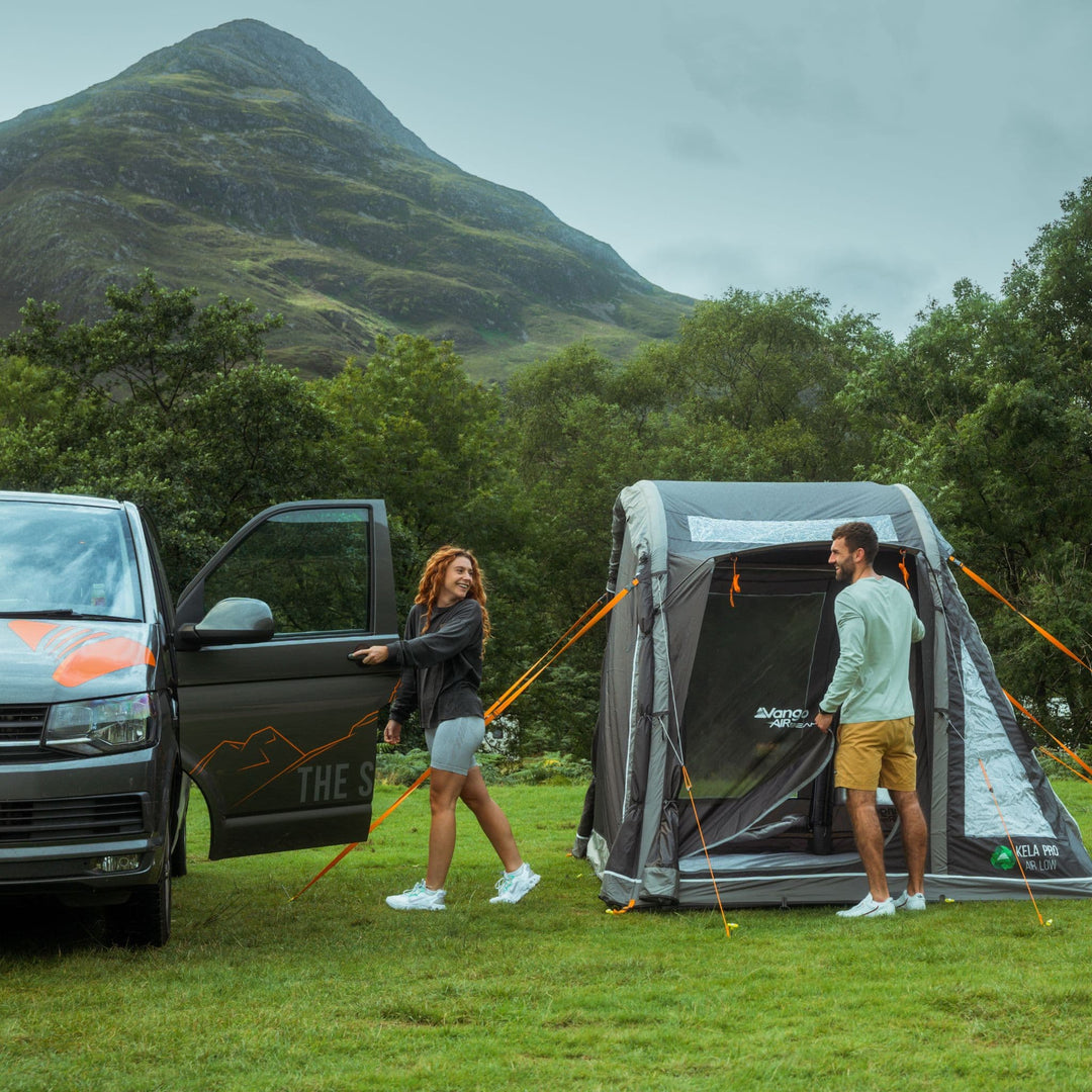 Couple standing next to the Vango Kela Pro Air Low Drive Away Awning detached from a campervan, showing its drive away capabilities.