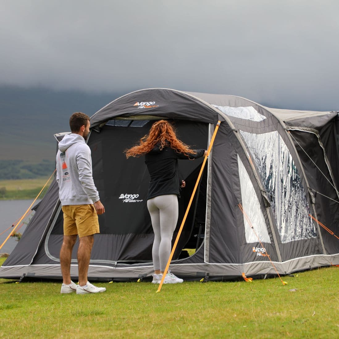 Couple entering the Vango Kela Pro Air Low Drive Away Awning attached to their campervan, highlighting the convenience and spaciousness of this inflatable campervan awning.