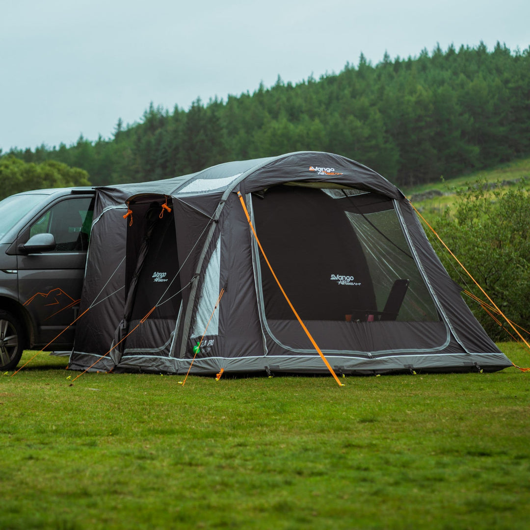 Vango Kela Pro Air Low Drive Away Awning attached to a campervan, set up in a lush green field, showcasing its secondary mesh doors for increased ventilation.