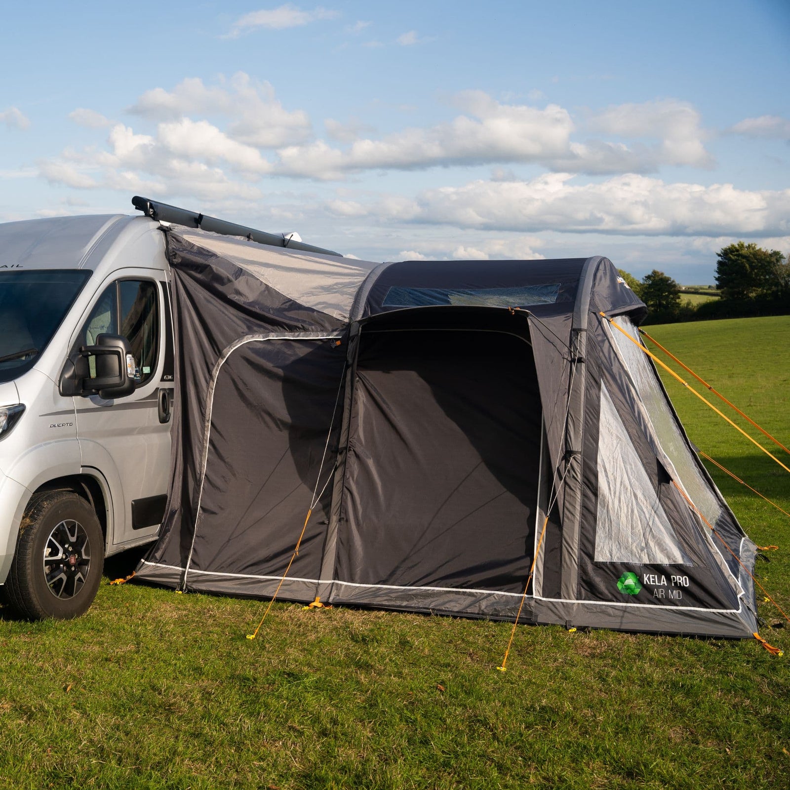 Full side profile of the Vango Kela Pro Air Mid Drive Away Awning attached to a campervan in a scenic outdoor setting, highlighting the inflatable campervan awning's durable structure.