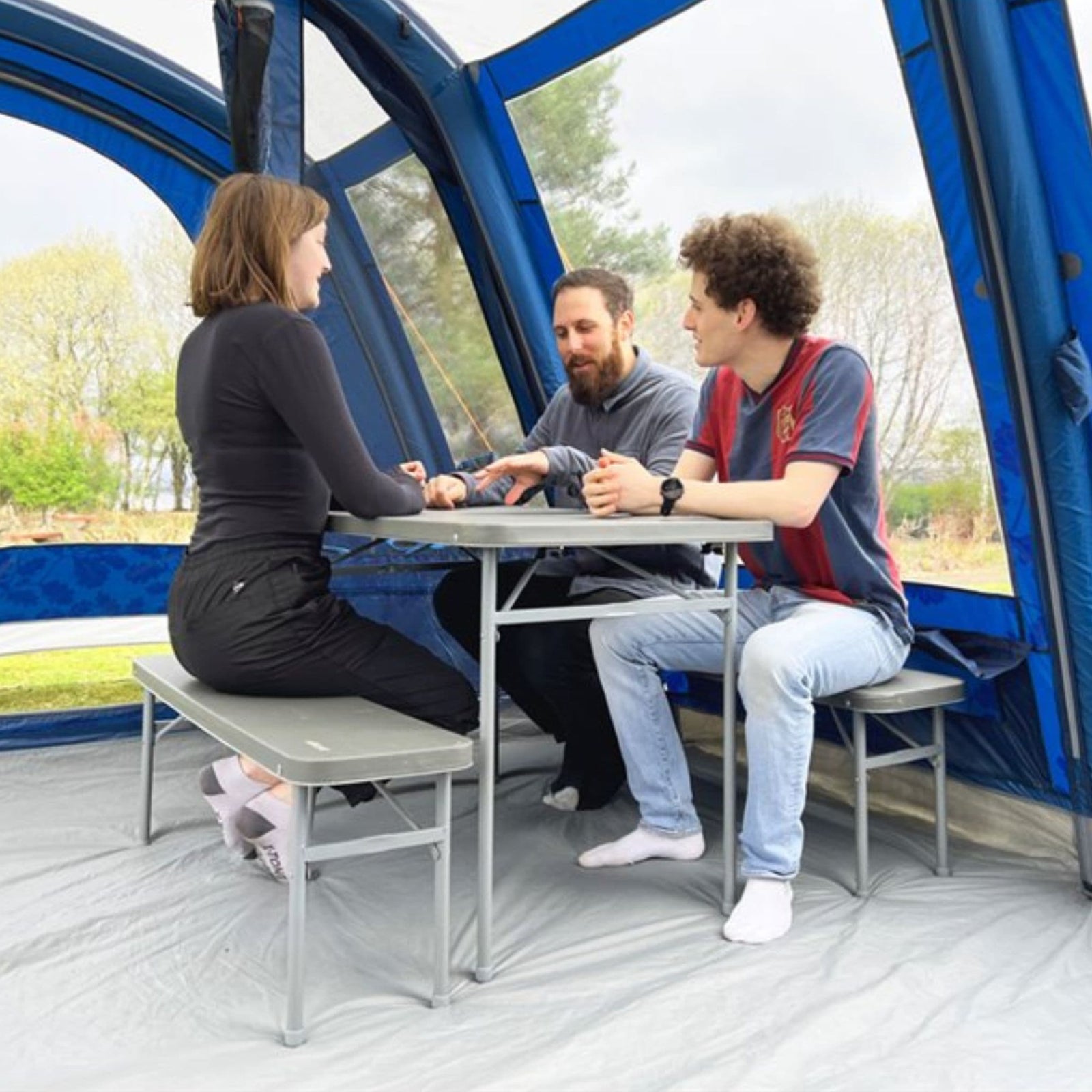 Group of three people enjoying a conversation at the Vango Orchard Bench Set, highlighting its comfortable and functional design for outdoor dining.