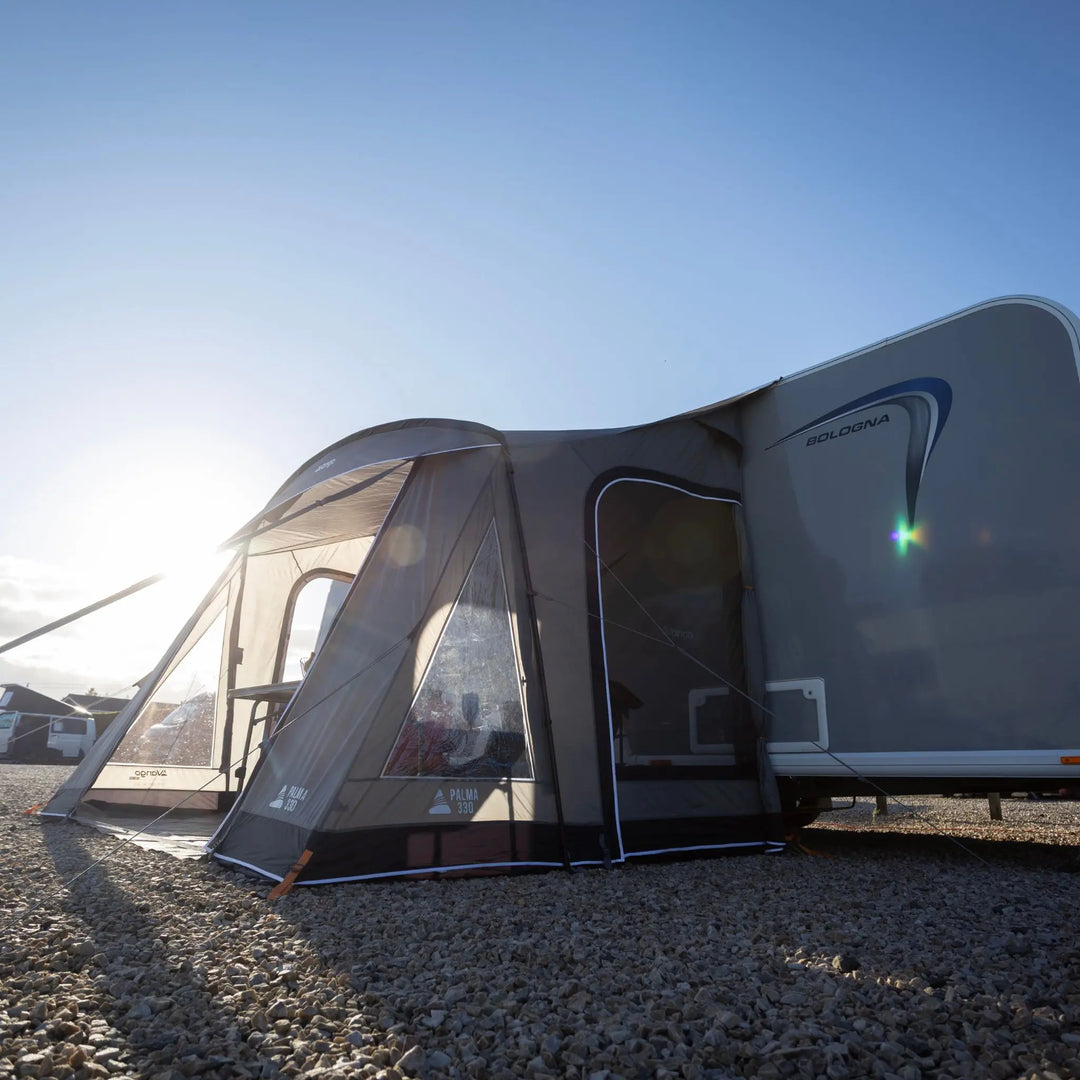 Vango Palma 330 Poled Caravan Awning attached to a white caravan on a gravel surface under a clear blue sky.