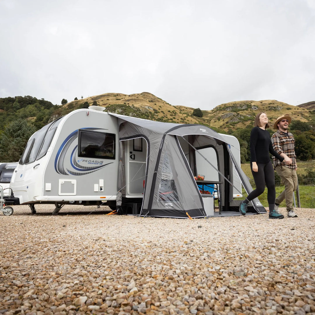 Lifestyle photo of a Vango Palma Air 260 Caravan Awning attached to a caravan on a hard-standing pitch with hills in the background.