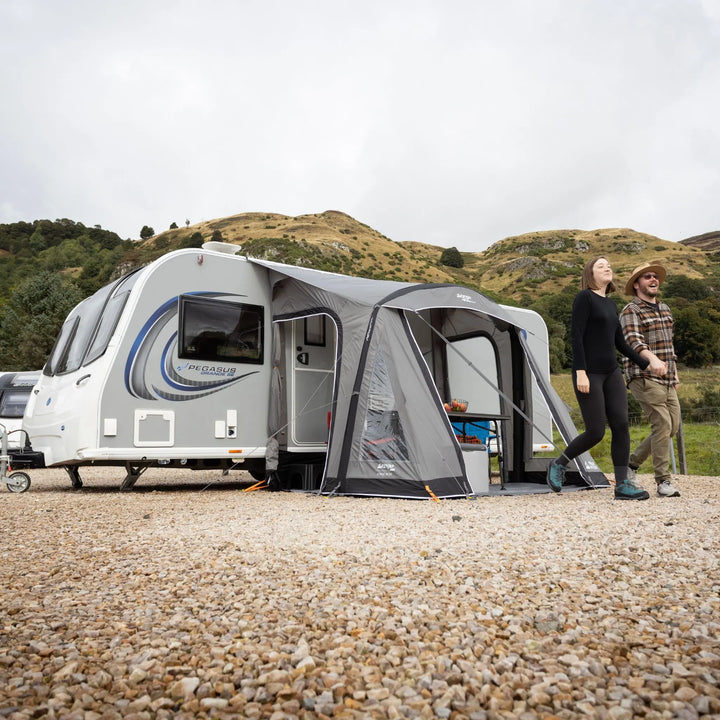 Lifestyle photo of a Vango Palma Air 260 Caravan Awning attached to a caravan on a hard-standing pitch with hills in the background.