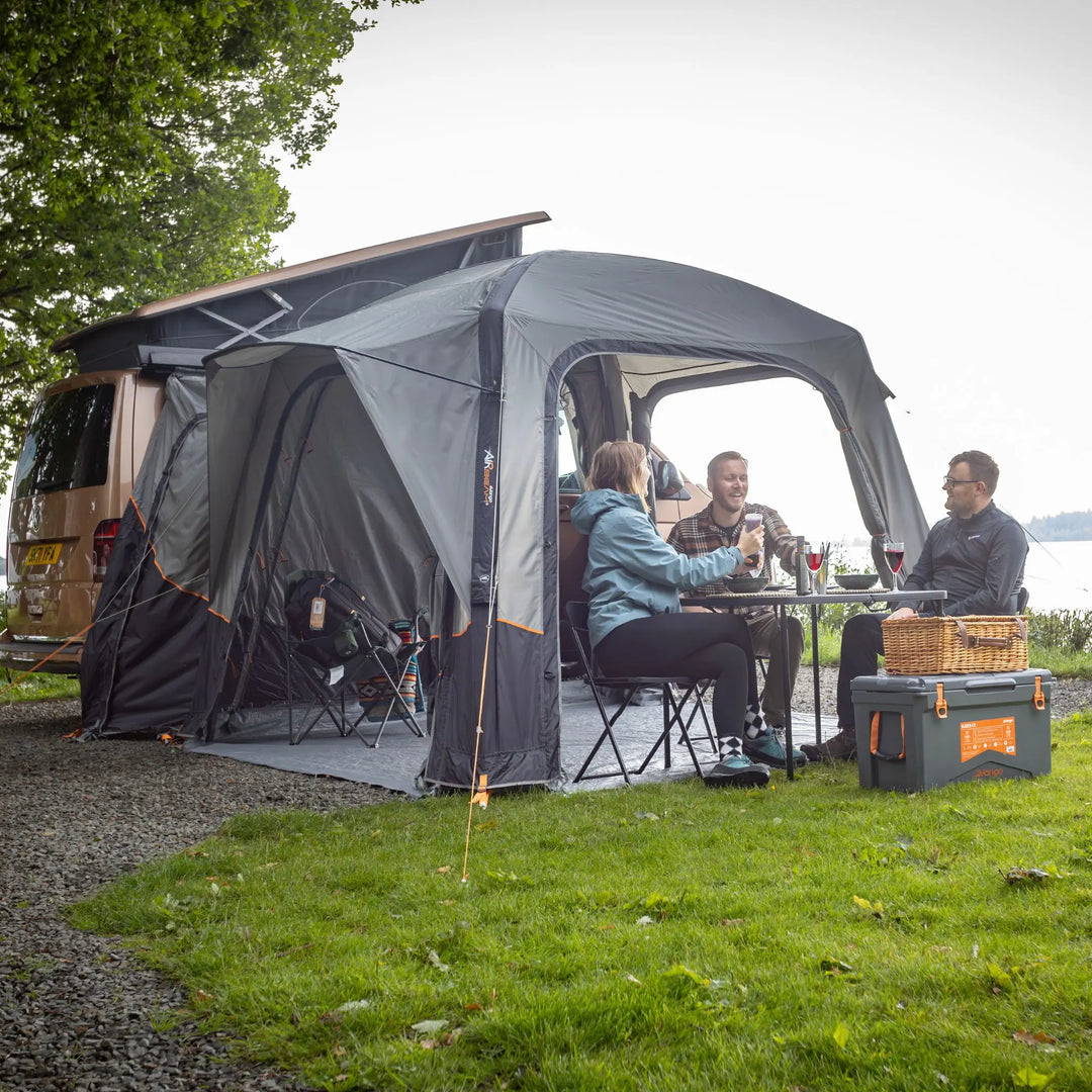 Lifestyle image of the Vango Quadris Air Low Drive Away Awning with people sat outside.