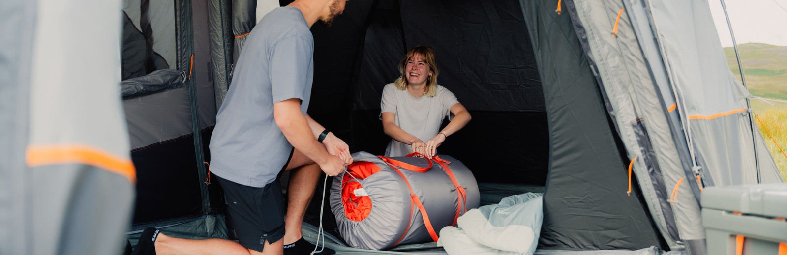 Couple packing the Vango Shangri-La II 15cm Double SIM inside a tent, showcasing its portability and camping convenience.