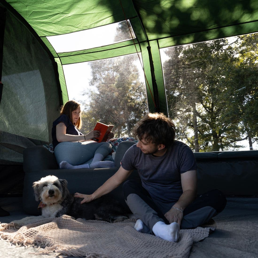 A couple and a dog relaxing inside the Vango Sherwood 400XL Poled Tent, highlighting the tent's large living area.