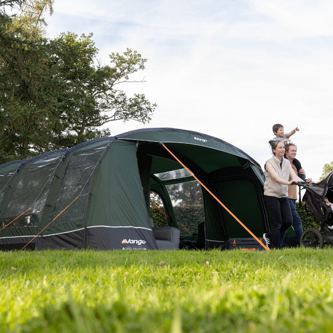 A mother and father walking with a stroller outside the Vango Sherwood 600XL Poled Tent, illustrating its practicality for families with children.