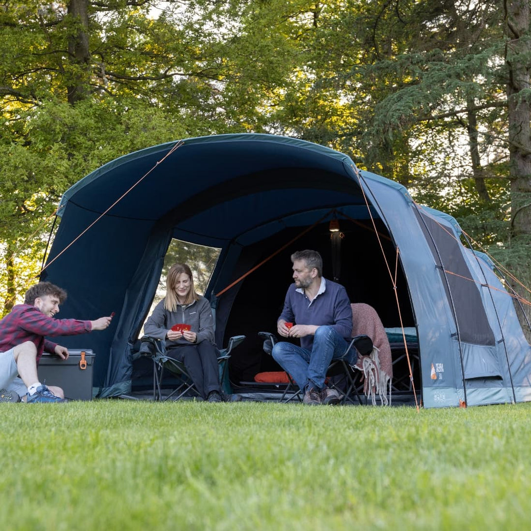 Close-up front view of campers relaxing in front of the Vango Sierra 500 Poled tent, highlighting the comfortable setup with chairs and gear.