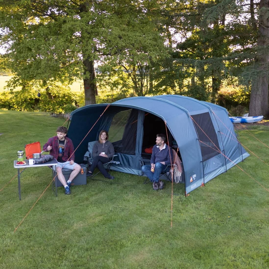 Group camping scene with the Vango Sierra 500 Poled tent pitched on a lush green field, highlighting its versatility and size for 5 people.