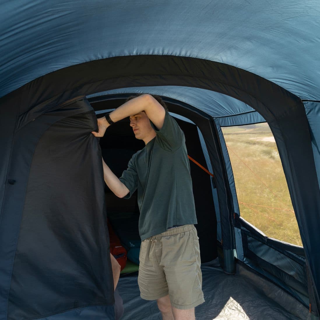 Camper adjusting the door of the Vango Sierra Air 300 3-man tent, showing its flexible layout ideal for couples.