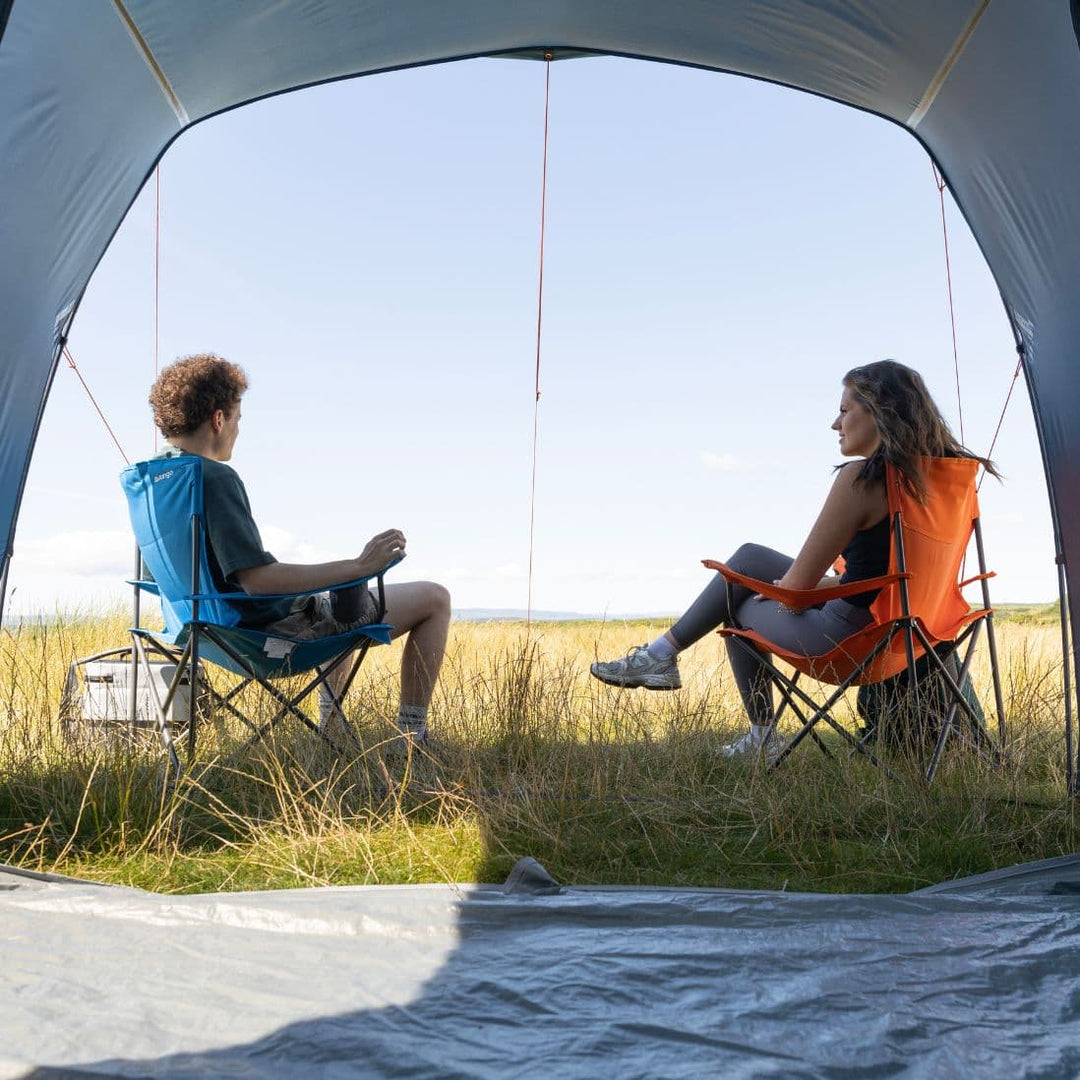 Campers seated outside the Vango Sierra Air 300 couples tent, enjoying the day with the tent’s front door open for easy access.