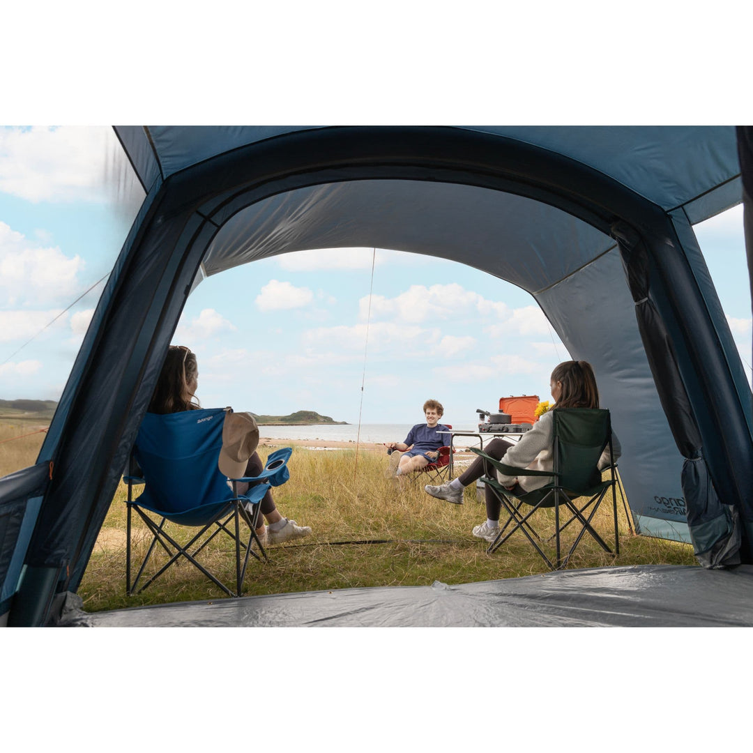 Front Canopy View of Vango Sierra Air 500 Tent: A view of the front canopy of the Vango Sierra Air 500 5-man tent, with people relaxing while enjoying the outdoor scenery through the large mesh roll-away door.