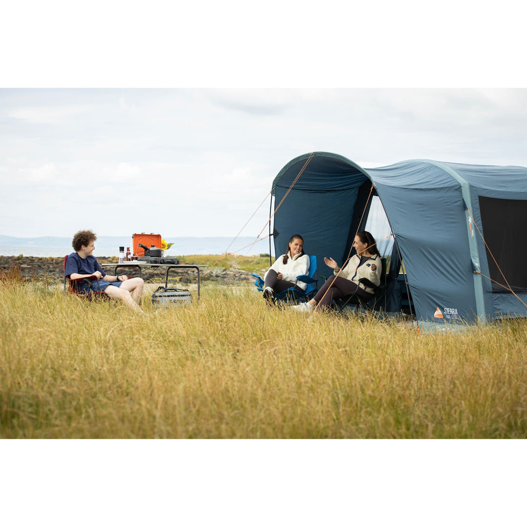 Two people relaxing under the canopy of the Vango Sierra Air 500 5-man tent, enjoying the outdoors with comfort and protection.