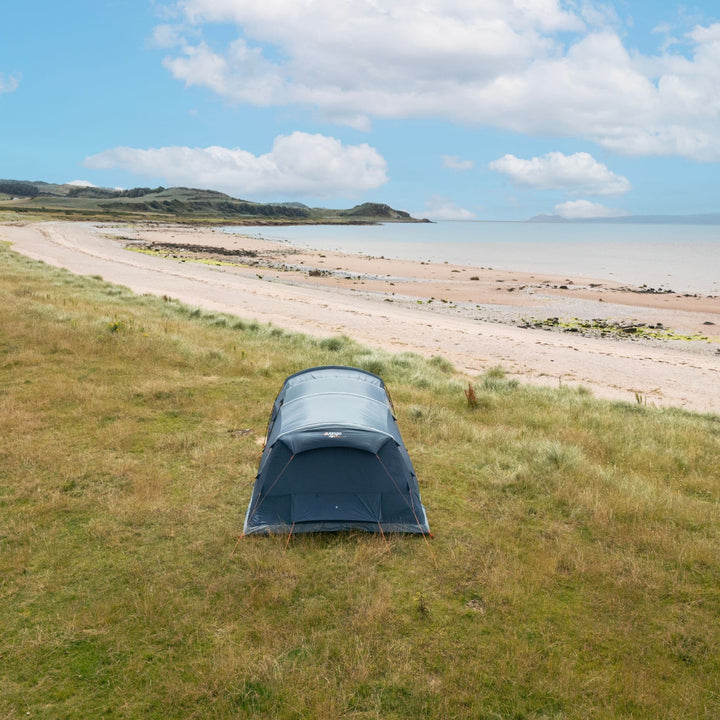 An aerial view of the Vango Sierra Air 500 5-man tent, demonstrating its layout and pitched structure in a spacious open field next to a beach.