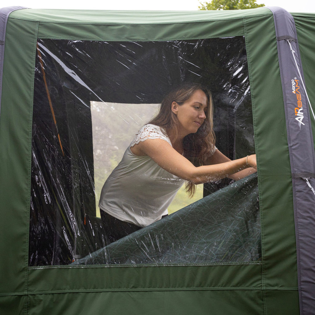 A camper taking down the curtons on the window of the Vango Sierra Air TC 300 AirBeam Tent