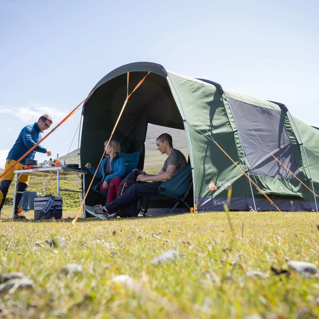 People sitting inside a Vango Sierra TC 300 Poled Tent in a grassy field on a sunny day.