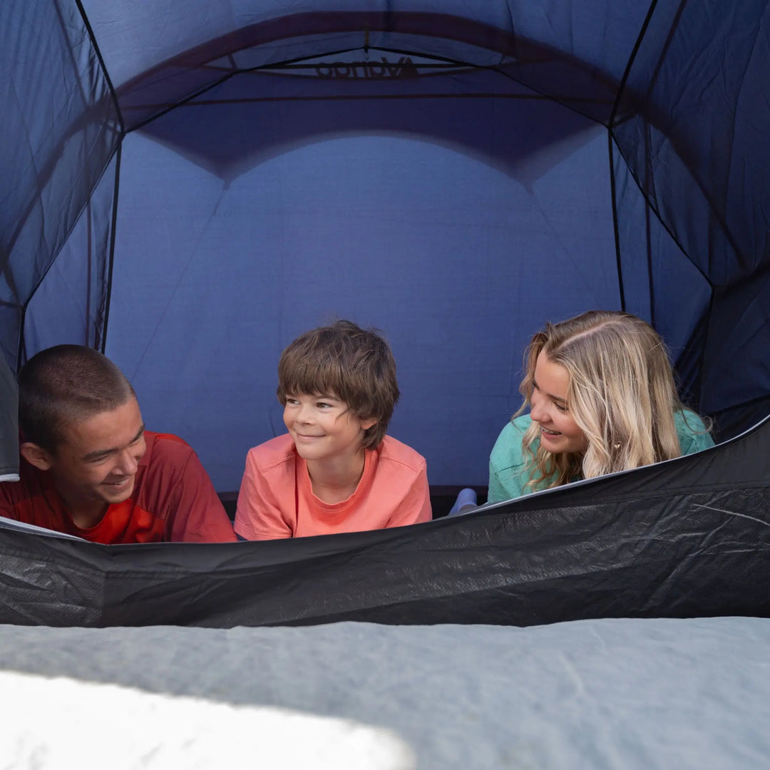 Three children inside a Vango Sorrento 600XL Tent, with one child looking outwards.