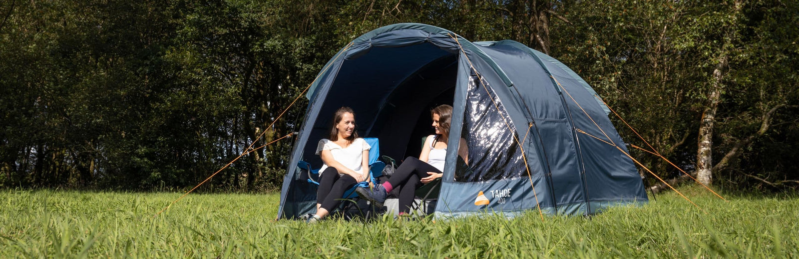 Vango Tahoe 400 4 man tent with two women sitting in chairs at the entrance, enjoying their camping experience.