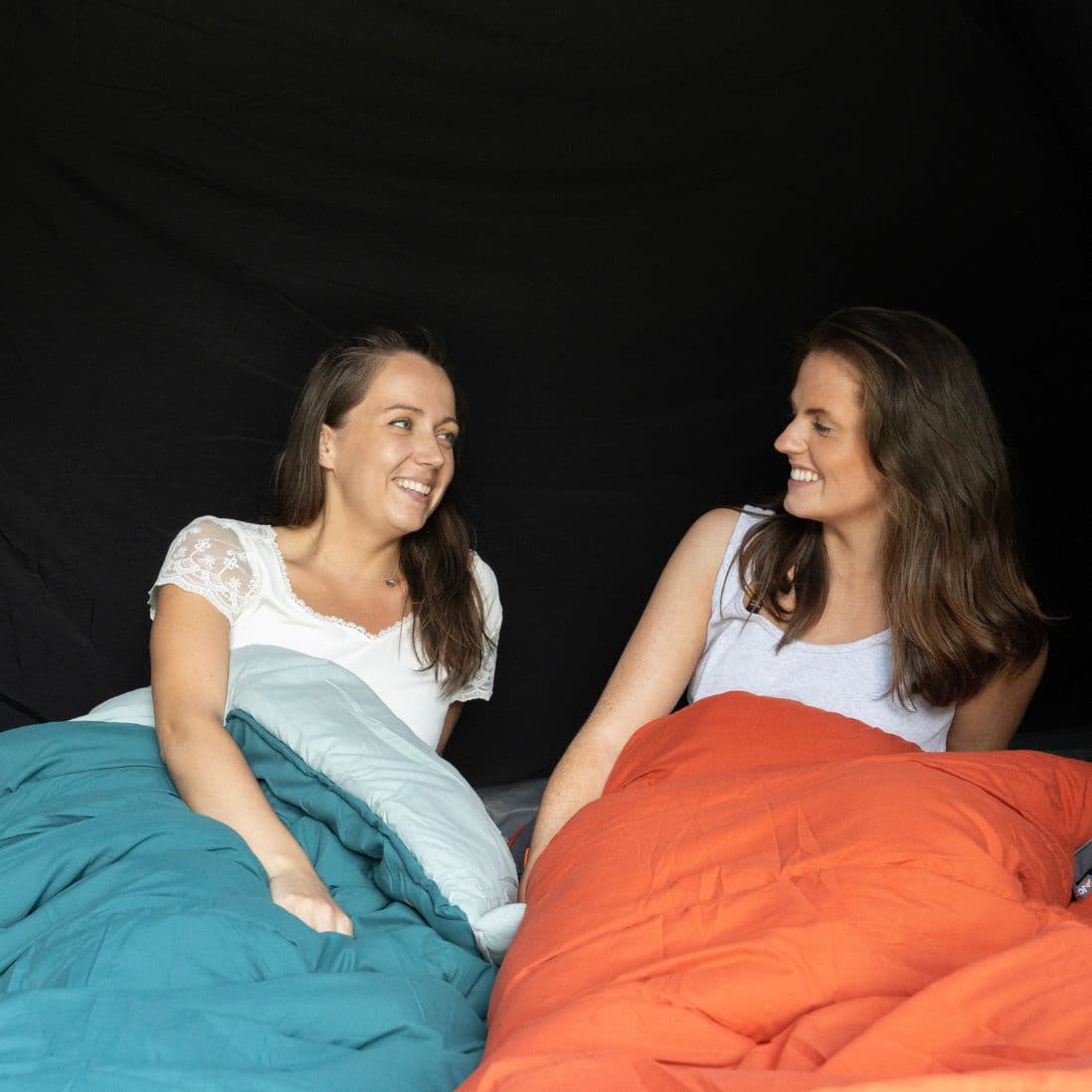 Inside the Vango Tahoe 400 4 man tent, showing two women lying in sleeping bags in the spacious interior.