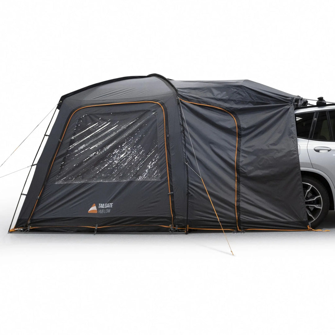 Angled view of the Vango Tailgate Hub II Low Awning connected to a car, highlighting the large window panels and secure attachment to a car.