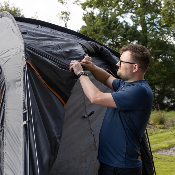 Man adjusting the awning connection tunnel to a campervan, demonstrating the roll away connection tunnel on the Vango Tailgate Hub II Low.