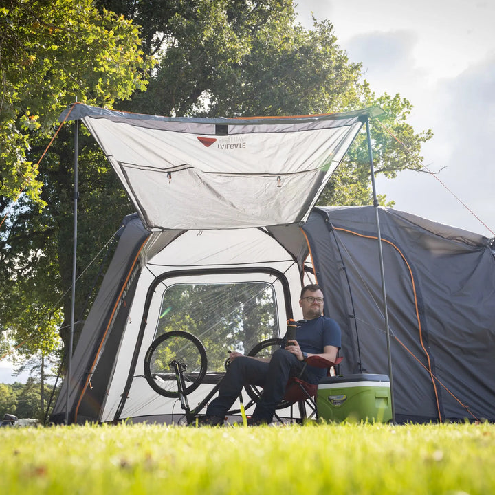 Cyclist storing a bike inside the Vango Tailgate Hub II Low awning, illustrating its suitability for campervan adventurers.