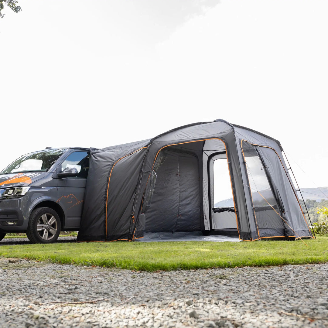 Scenic lake and mountain view framed through the rear window of the Vango Tailgate Hub II Low awning, highlighting its secure connection to campervan.