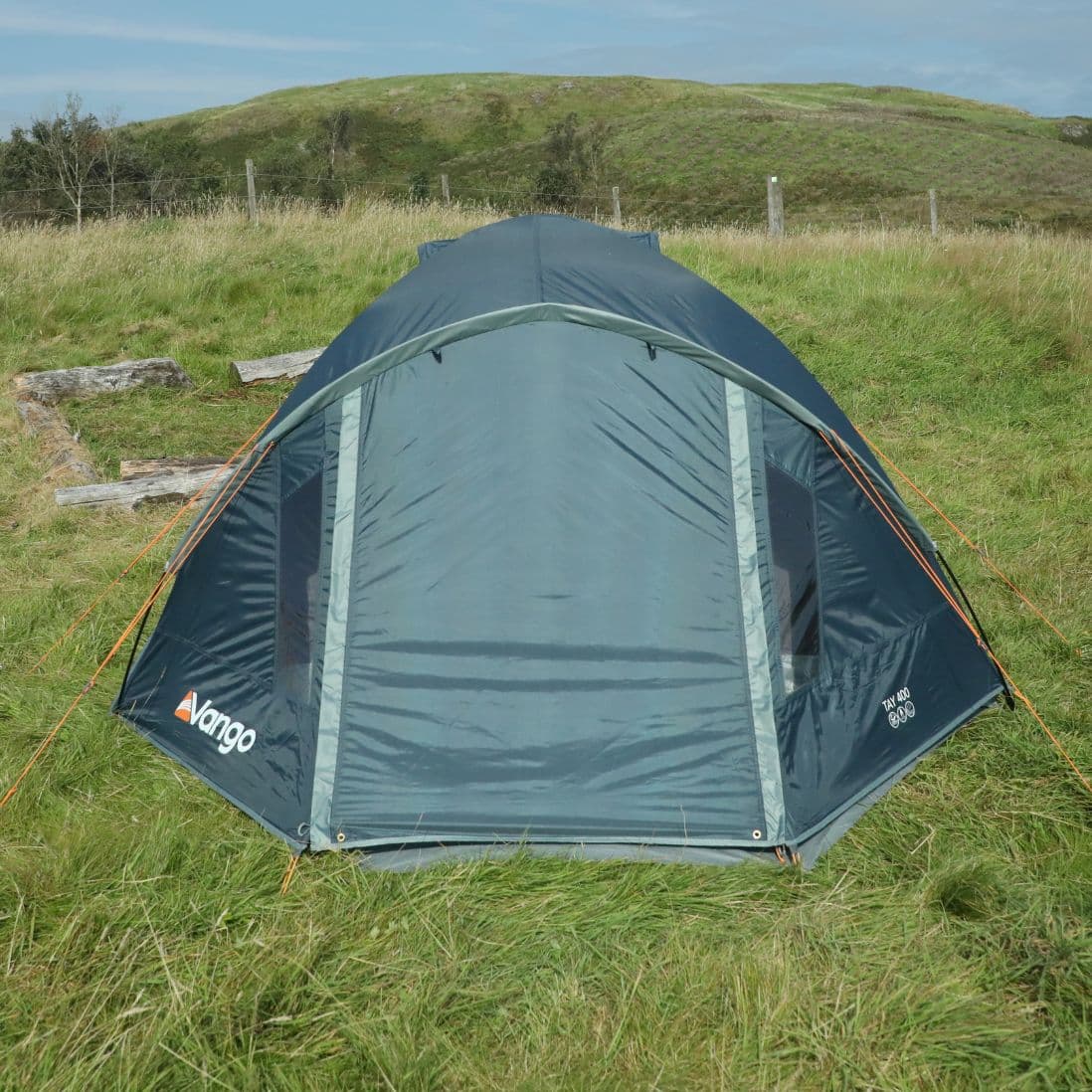 Front view of the Vango Tay 400 4-man tent set up with the door closed at a campsite, perfect for festivals, highlighting its weatherproof design and compact size.